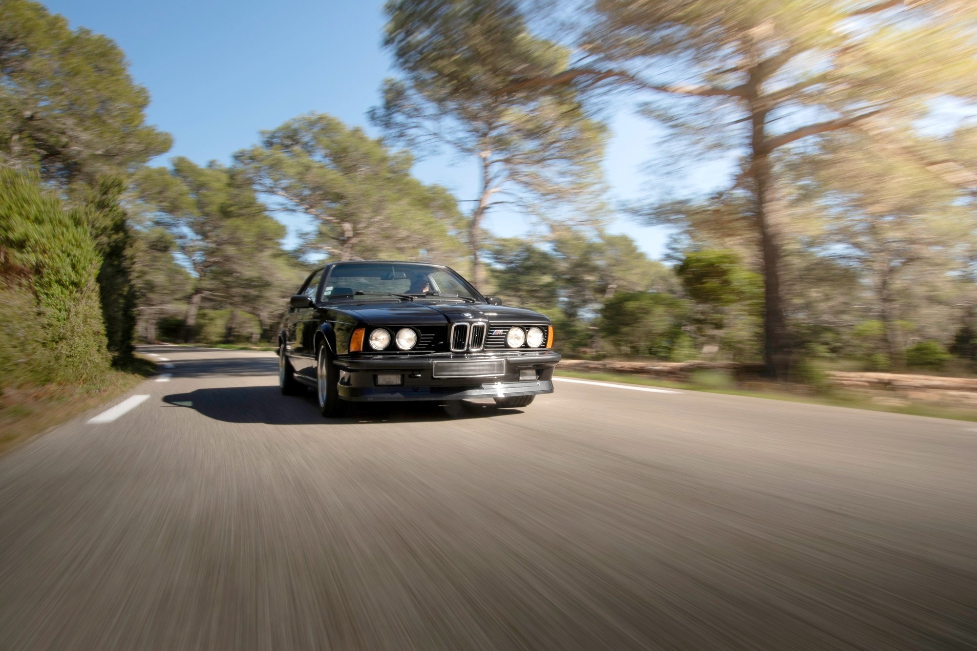 BMW M635 CSi noire de trois-quarts avant au coucher du soleil, jantes BBS
