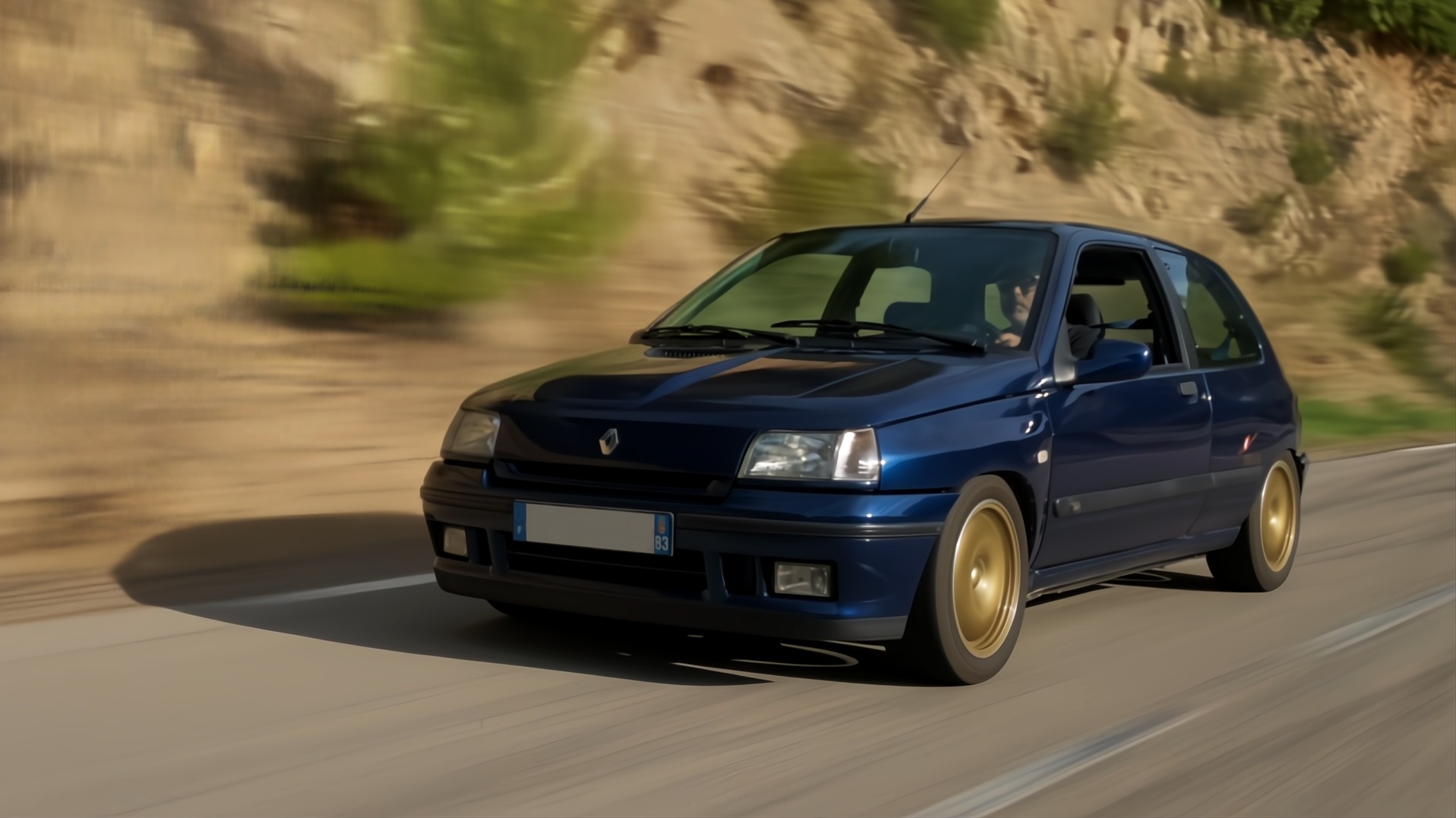 Renault Clio Williams bleue en action sur route sinueuse